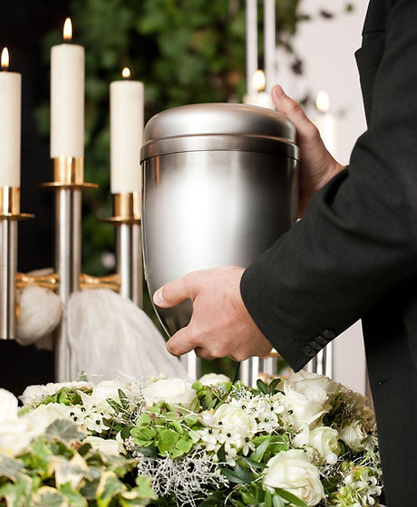 death and dolor - funeral and cemetery, mortician carrying the urn to a bed of white roses.jpg