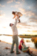 Family on beach with dad swinging daughter in the air