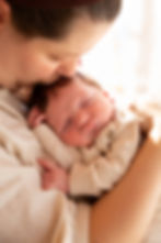 Mom holding newborn son, Caleb, while kissing his forehead
