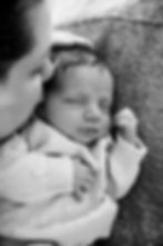 Mom kissing newborn's forehead while he is sleeping