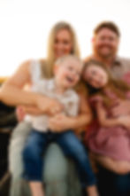 Children laughing while being held by their parents on the beach