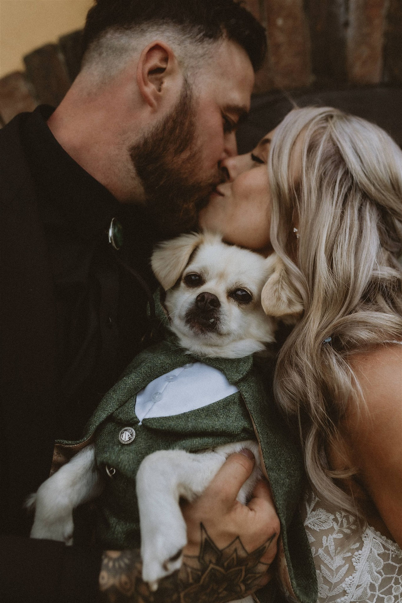 bride and groom kissing whilst holding their dog who is dressed as Frodo Baggins from Lord of The Rings 
