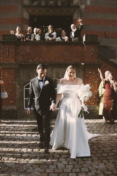 Georgia and Will walk through confetti outside The Pumping House wedding venue