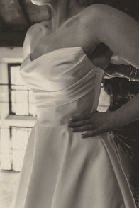 Georgia fastening her white off-the-shoulder wedding dress