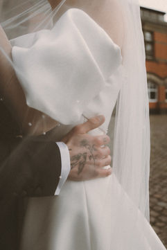 Close-up of Will holding Georgia’s waist during relaxed wedding portraits
