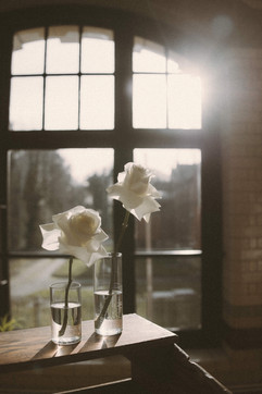 White roses in glass vases beside an arched window