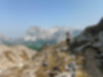 Hiker walking along a rocky Dolomites trail overlooking Passo Falzarego and the Fanes‑Sennes‑Braies Nature Park near Cortina d’Ampezzo.
