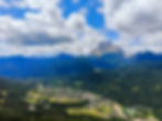 Mountain valley with a town, river, and cloudy sky