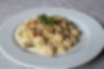 Homemade potato gnocchi with mixed cheese sauce and chopped walnuts served at Rifugio Scotter in the Dolomites.