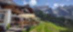 Rifugio Scotter mountain hut with wooden terrace and umbrellas overlooking Pelmo peak in the Dolomites near Cortina d’Ampezzo.