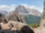 View of the 5 Torri rock formations with the Tofana di Rozes towering in the background, surrounded by forests and rugged Dolomites peaks near Cortina d’Ampezzo.