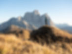 Hiker standing on a grassy summit facing Monte Pelmo in the Dolomites, enjoying panoramic mountain views during a guided Bike & Hike experience.