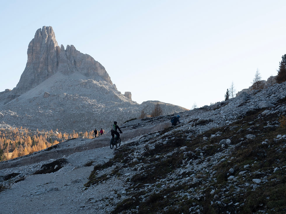 Cyclist and hikers on rocky Dolomites trail below Becco di Mezzodì near Rifugio Palmieri, part of a guided Bike & Hike experience from Cortina.