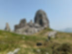 Hiker walking toward the 5 Torri rock formations in the Dolomites near Cortina d’Ampezzo on a clear summer day.