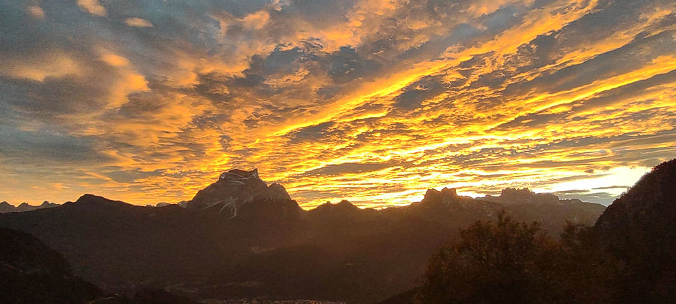 Sunset over Mount Pelmo in the Dolomites, with glowing orange clouds and mountain silhouettes near Rifugio Scotter.