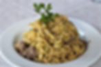 Homemade tagliatelle with venison ragù served at Rifugio Scotter, a traditional Dolomites dish with fresh parsley garnish.