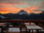 Sunset view from Rifugio Scotter overlooking Mount Pelmo and San Vito di Cadore, with snow‑covered terrace and glowing orange sky over the Dolomites.