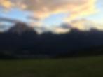 Evening view of Mount Pelmo and the Dolomites above San Vito di Cadore, with golden clouds and soft sunset light over alpine forests.