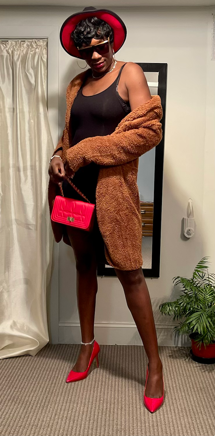 Thumbnail: Woman in brown coat holding red purse near mirror and plant