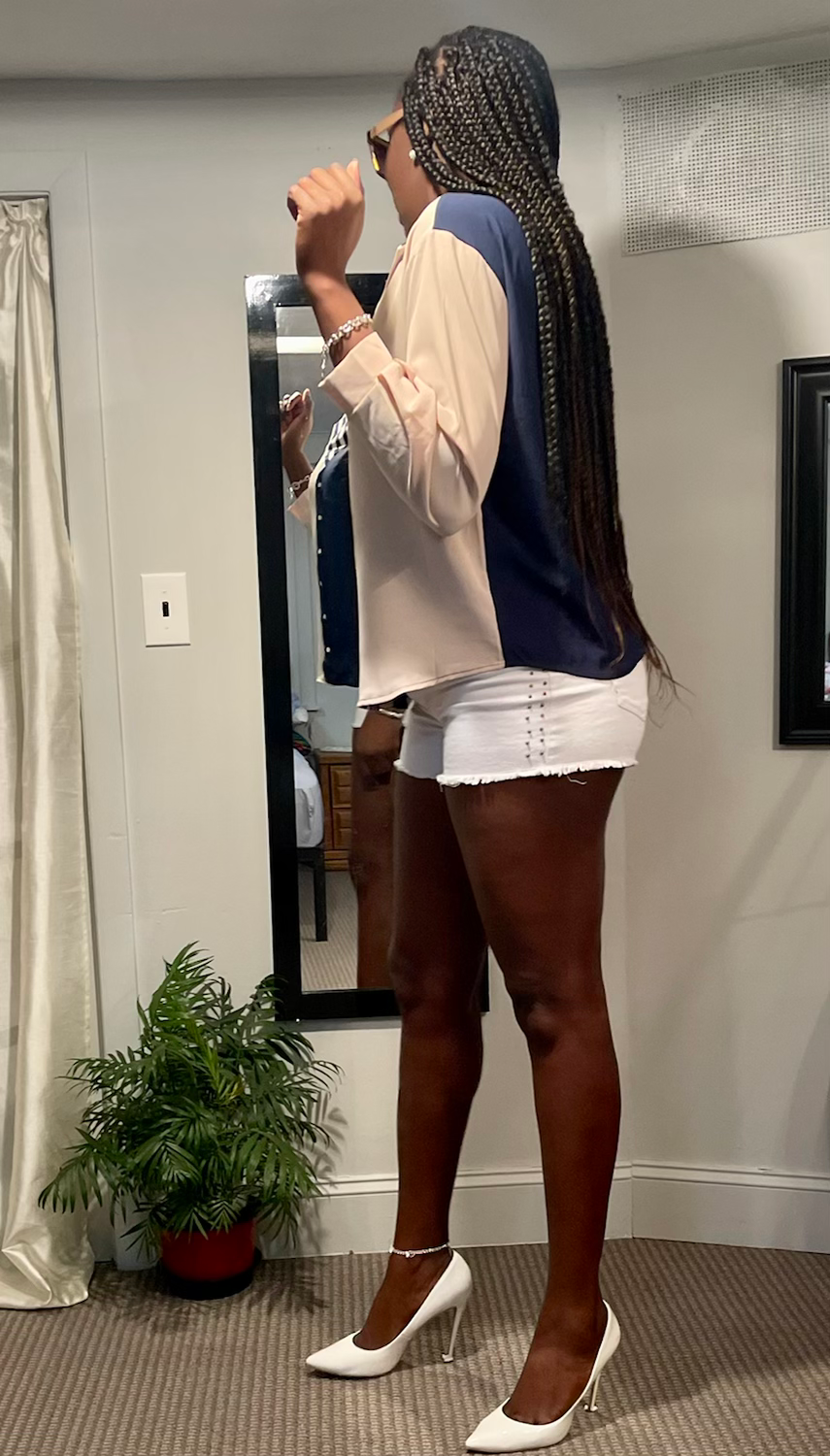 Thumbnail: Woman in white shorts and color-lump patchwork blouse poses next to mirror.