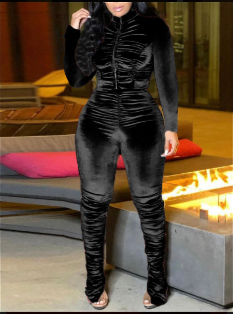 Thumbnail: Woman in a black velvet outfit, standing near an outdoor fireplace.