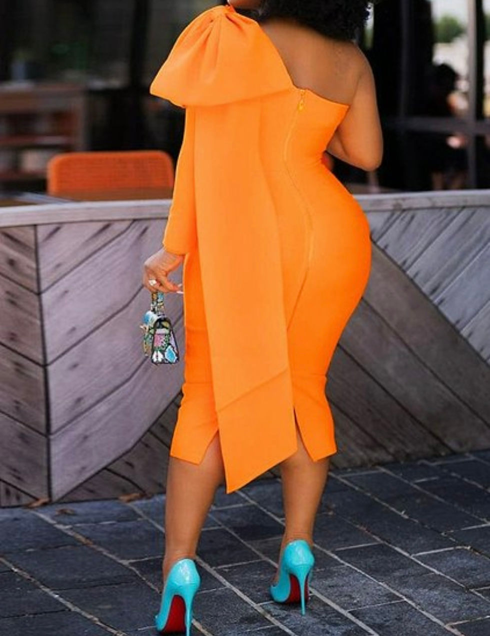 Thumbnail: Woman in orange dress, holding a purse, standing with Madame Curves
