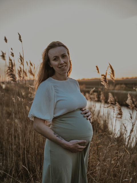 Een zwangerschapsshoot met zonsondergang met een zwangere jonge vrouw.