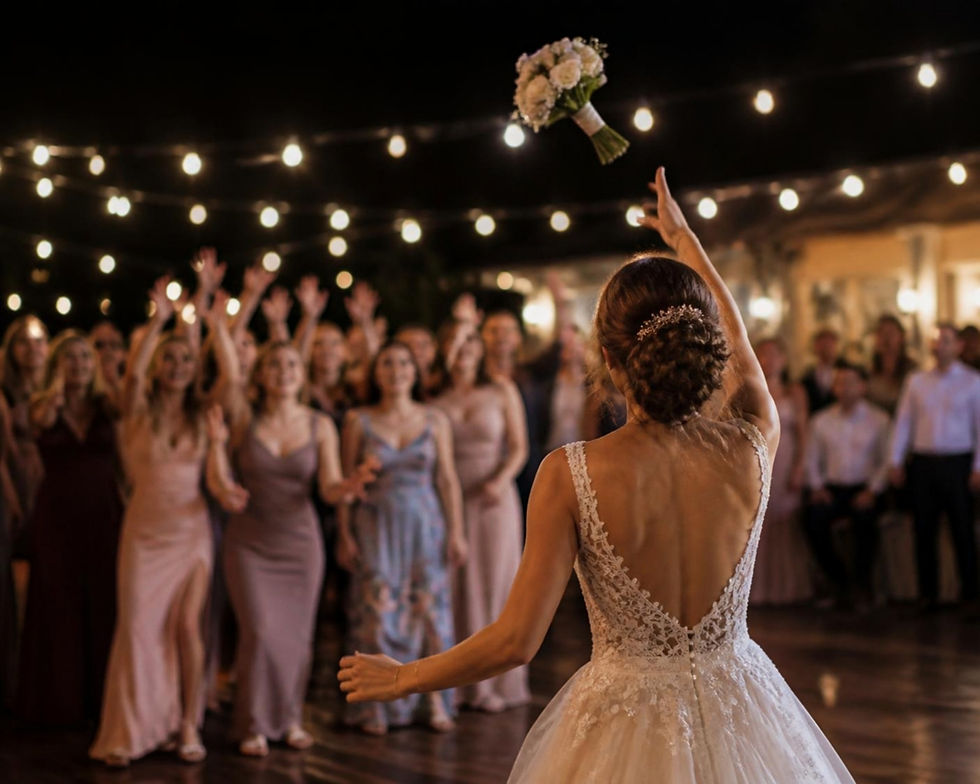 Bride tossing her bouquet to guests at a wedding reception under string lights