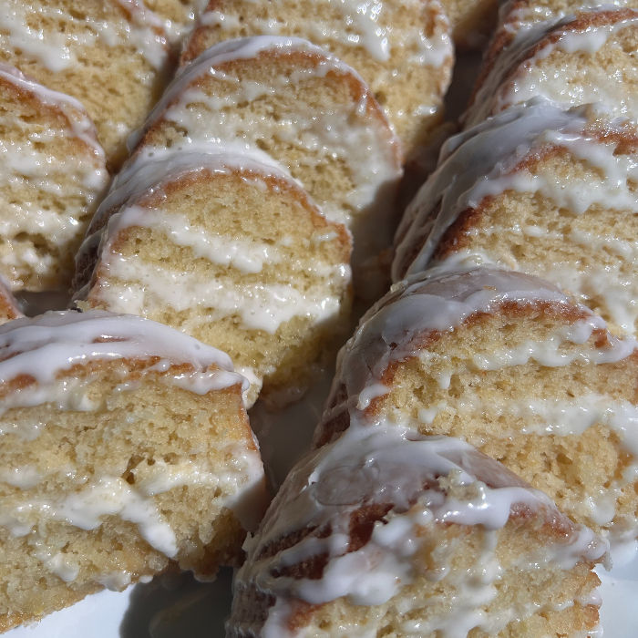 The Best Lemon Cake Sliced into 15 pieces and placed on a white platter drizzled with a creamy lemon glaze.