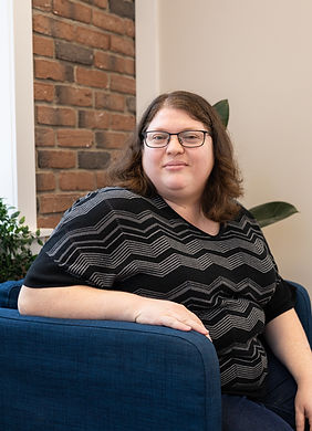 Therapist smiling while sitting on a blue chair in a therapy office in London, Ontario.
