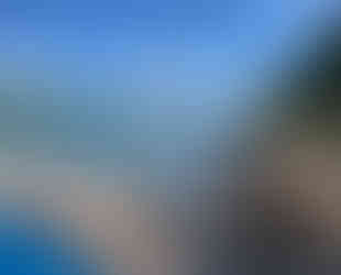 Large wooden deck near the water, trees and rocks.