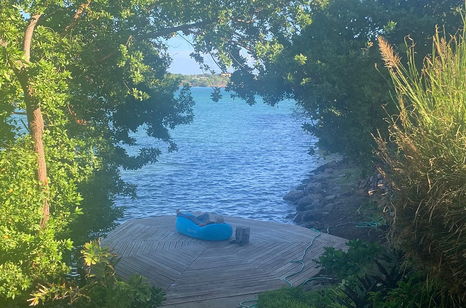 A person resting on a large wooden deck near the water.