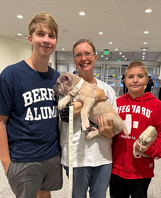 Lady holding a puppy with a child on either side of her