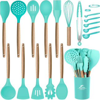 Teal silicone kitchen utensil set with wooden handles including spatulas, spoons, whisk, and ladle alongside an amber glass soap dispenser on a wooden tray.