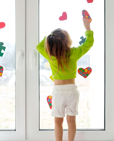 una-bambina-decora-la-vetrina-con-cartoline-con-cuori-e-puzzle-per-la-giornata-dell-autism