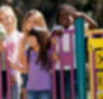 A group of cheerful children playfully standing on a colorful playground slide, ready to take turns sliding down.