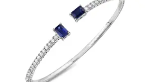 White Gold bracelet with two square blue sapphire gemstones and a row of small diamonds, set against a white background. Elegant and luxurious design.