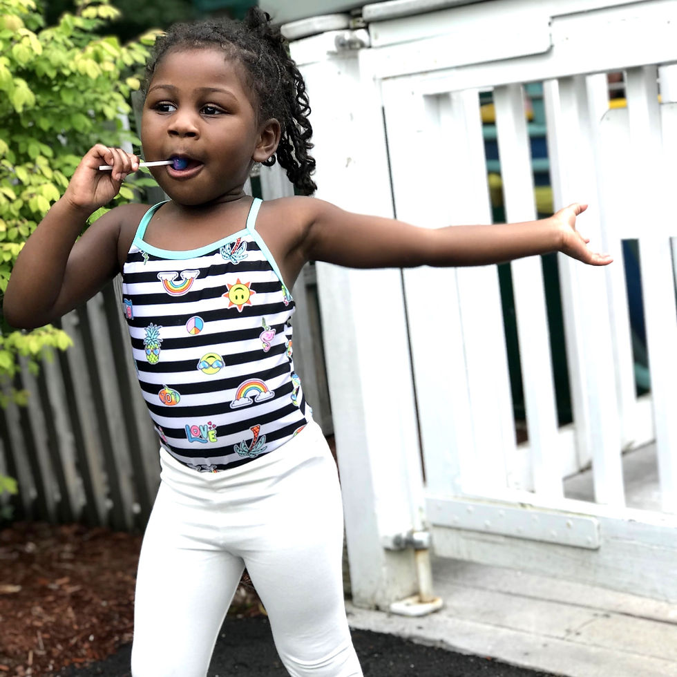 4 year old homeschooler wearing plaits standing in front of a white fence