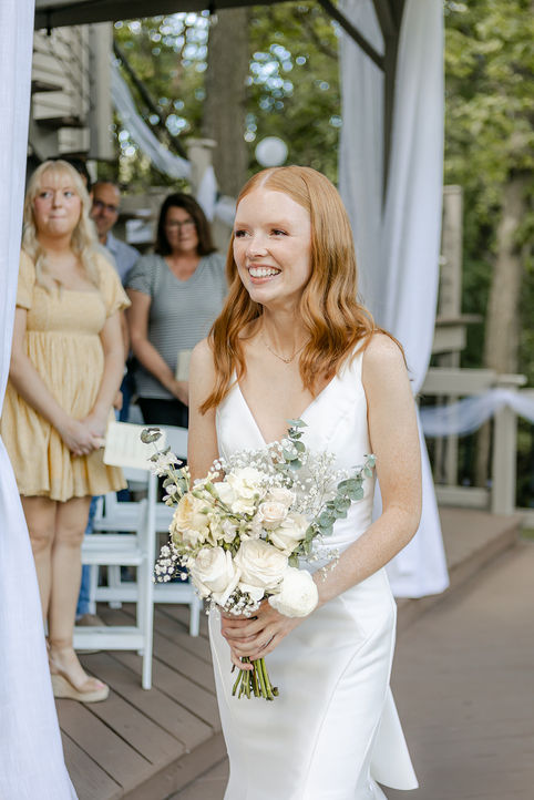 bride smiling towards groom as she walks down the aisle