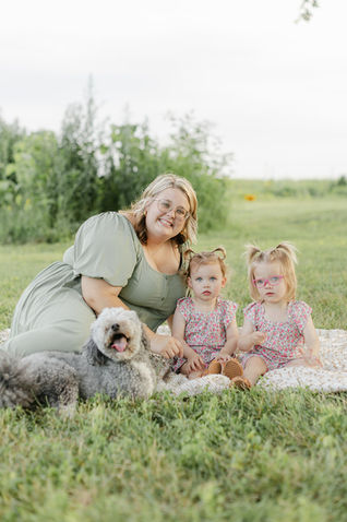 a mom sitting with her toddler girls and dog at their backyard in Murfreesbor