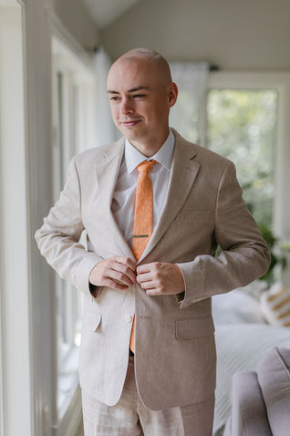 groom buttoning his suit while getting ready for his backyard Murfreesboro wedding