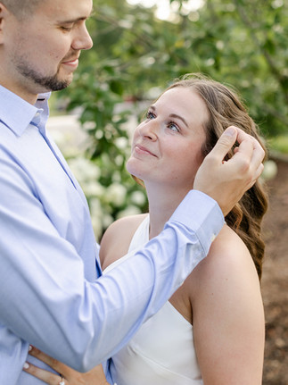 bride to be looking lovingly at future groom while he brushes hair behind her ear