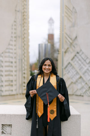 Purdue Graduate standing in front of the engineering fountain with bell tower in the backgrounds.