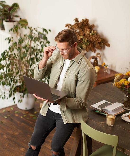 handsome-manager-man-glasses-sits-table-holds-laptop-types-sends-message-works-project-min