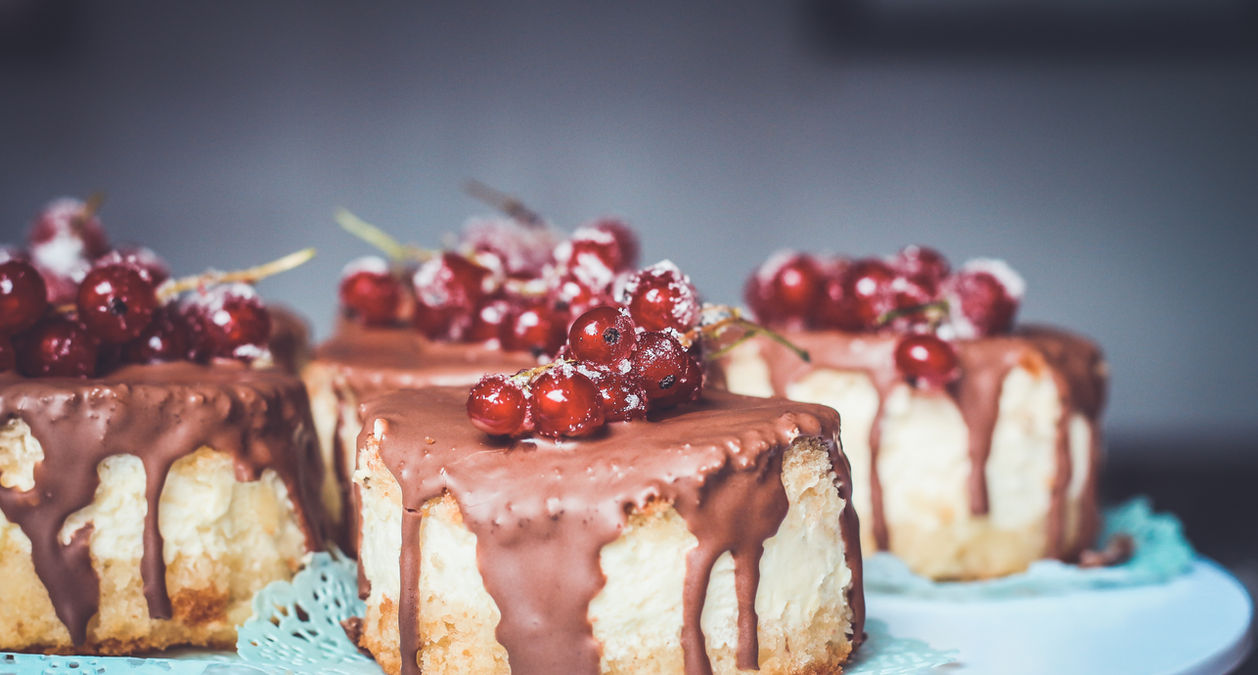 Mini cheesecakes by Suikerbekkie in Heist-op-den-Berg, decorated with rich chocolate drip and red berries for a luxurious dessert presentation.