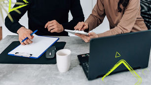 zwei Leute am Schreibtisch mit Laptop und Notizen