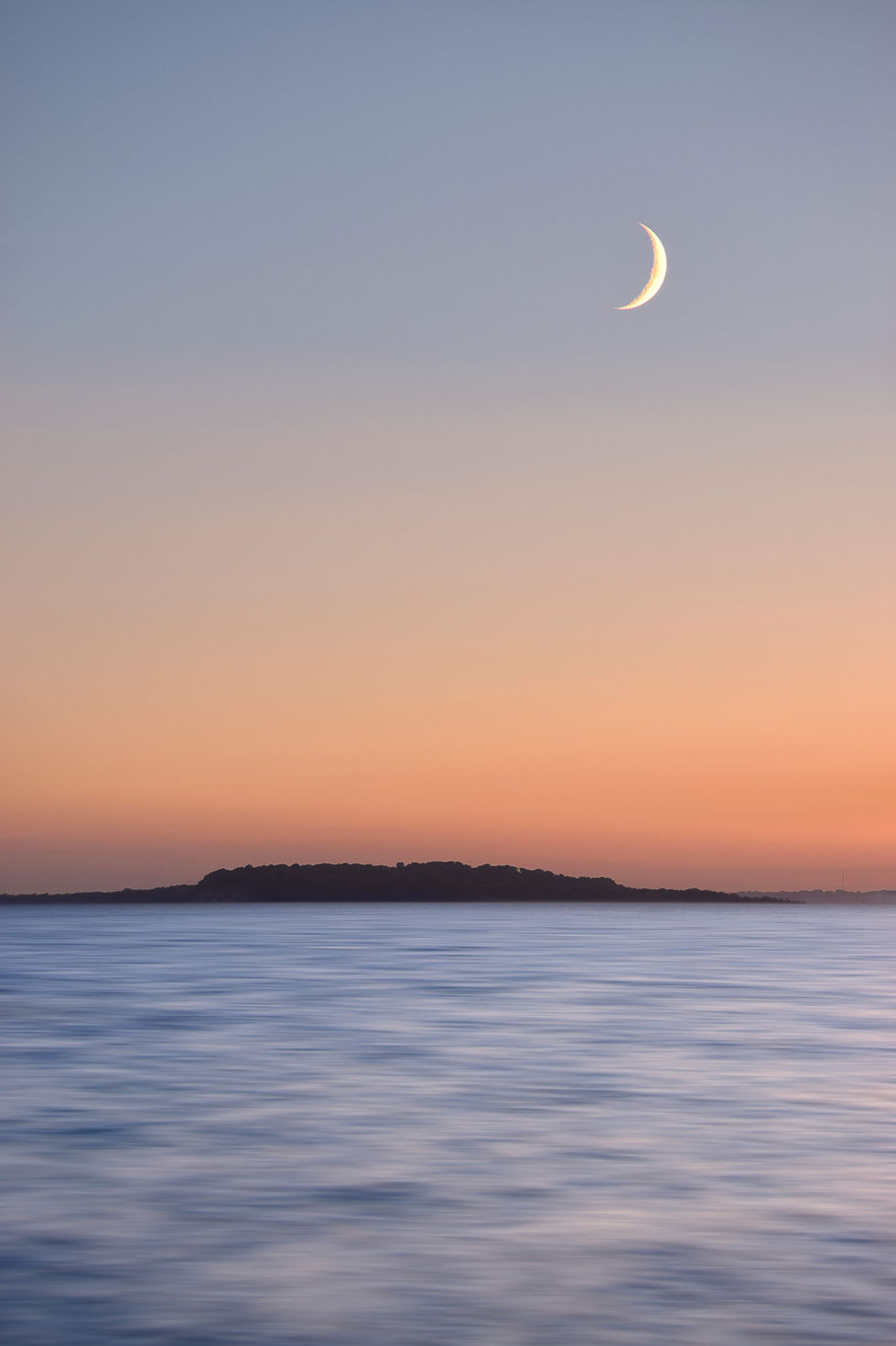 Blick auf die Insel Vilm im Licht des Sonnenuntergangs mit einem wunderschönen Sichelmonduntergang.