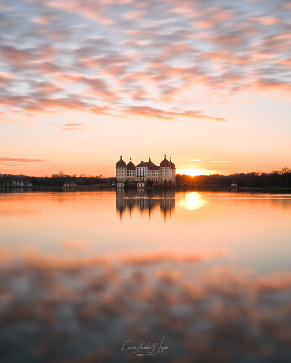 Sonnenuntergang am Schloss mit perfekter Wasserspiegelung.