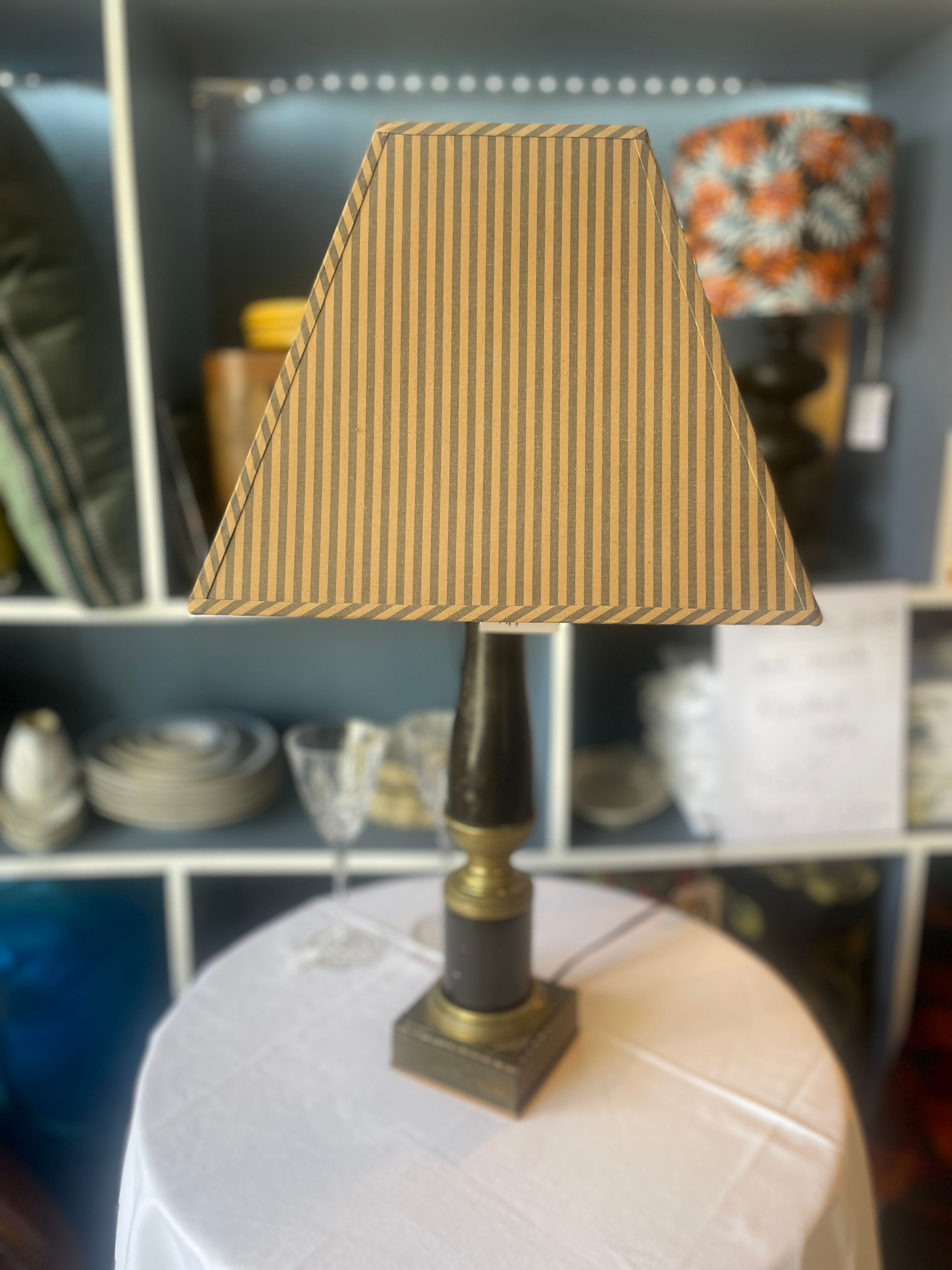 Lampe à poser style Napoléon III avec pied noir patiné, détails dorés et abat-jour rayé brun et doré.