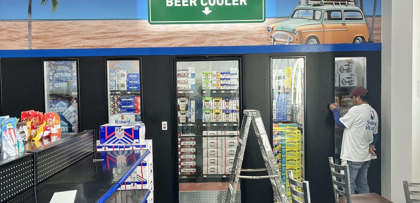 Mello Signs employee installing a graphic vinyl wall wrap on the interior walls inside a gas station in Dallas DFW, Texas.
